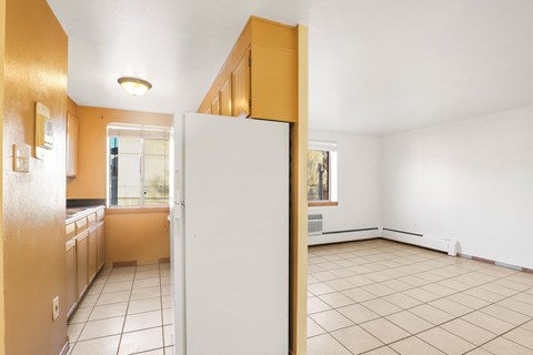 A kitchen with a white refrigerator and brown cabinets.